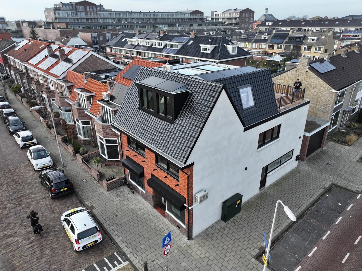 Luchtfoto van dezelfde woning na afloop: wit gestuukte gevels en een nieuw donker dak