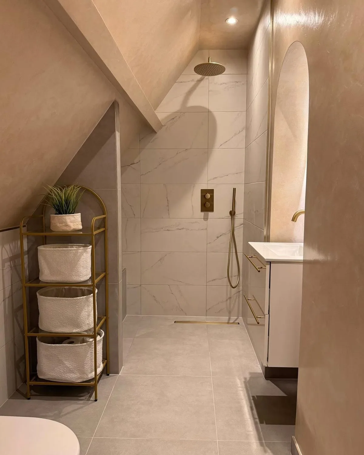 Badkamer in beige marmerlook met inloopdouche, goudkleurige regendouche en wastafelmeubel