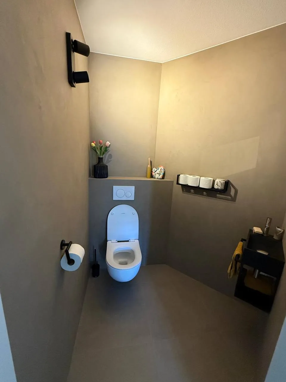 Toilet met grijze wanden, een hangtoilet en zwarte accessoires
