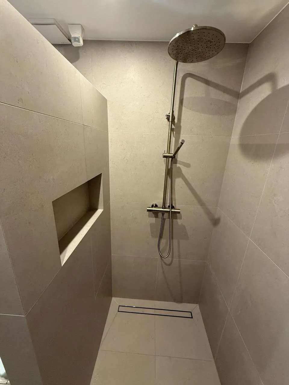 Inloopdouche met regendouche en een nis in de wand, in lichte tegels