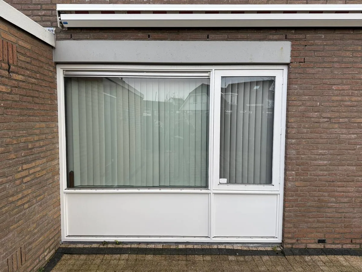 Wit kunststof kozijn in een bakstenen gevel, van buiten