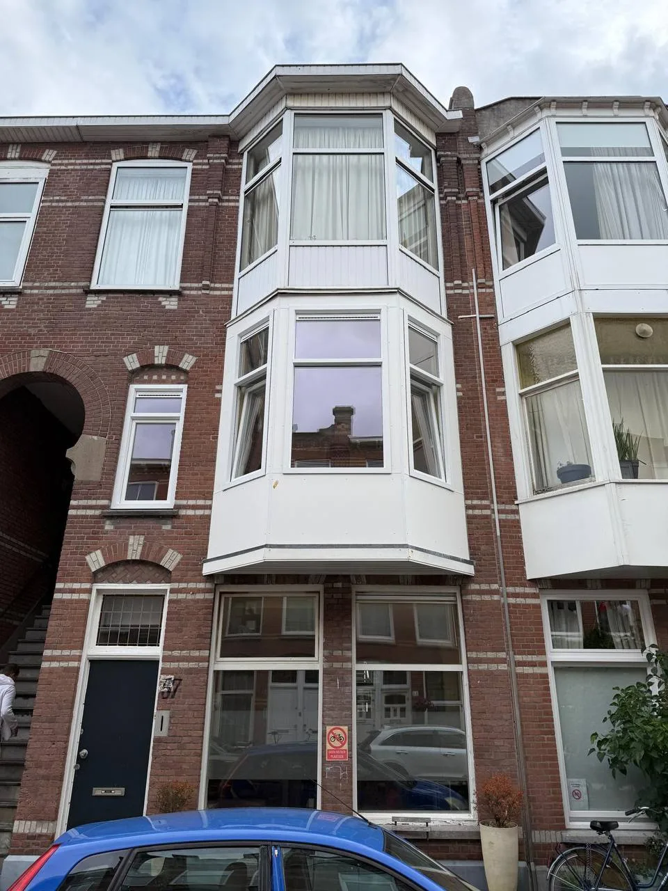 Bakstenen herenhuis met een witte erker en nieuwe witte kozijnen