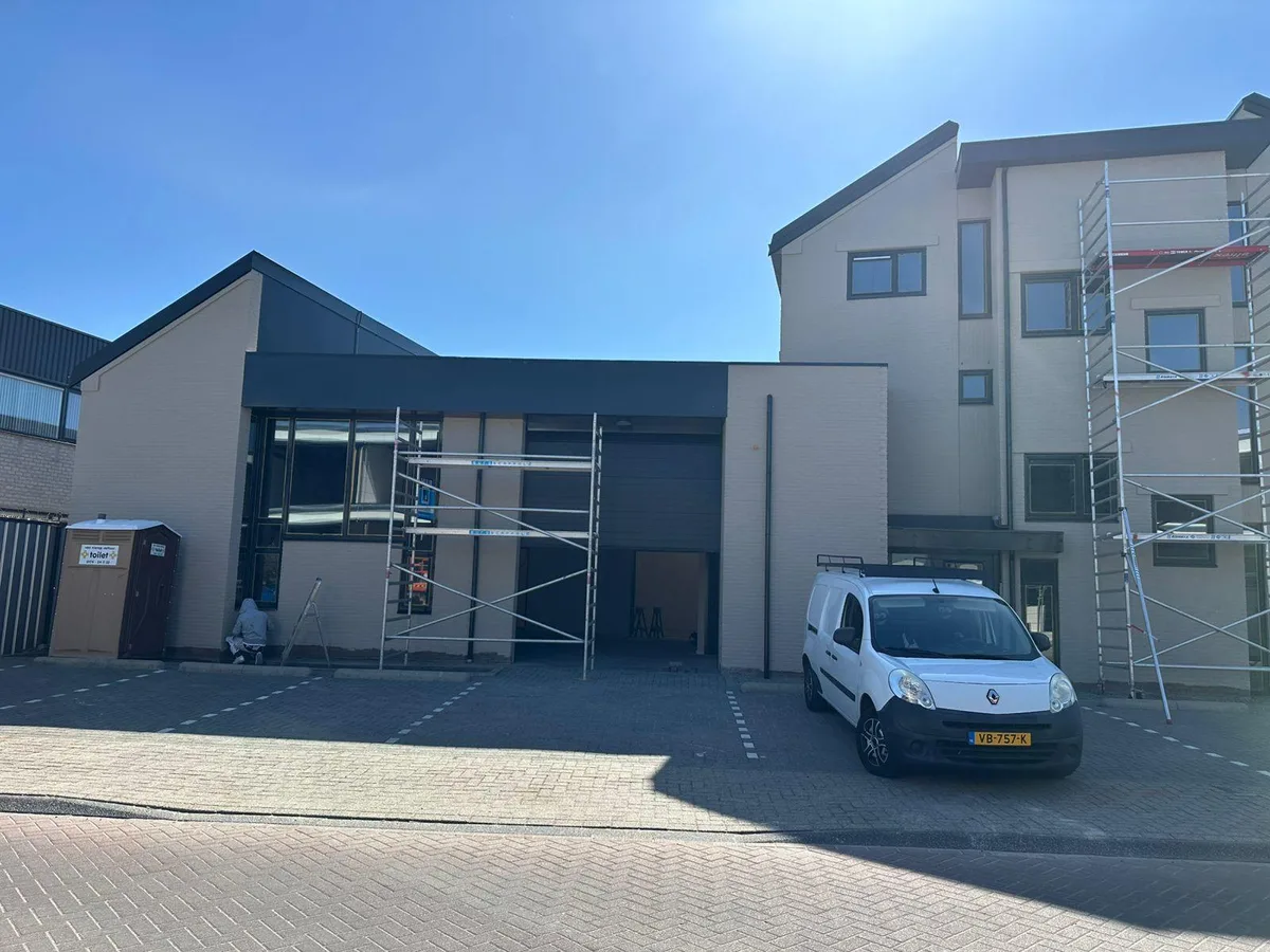 Entree van het bedrijfspand na het schilderwerk, met de steiger nog aan de zijkant