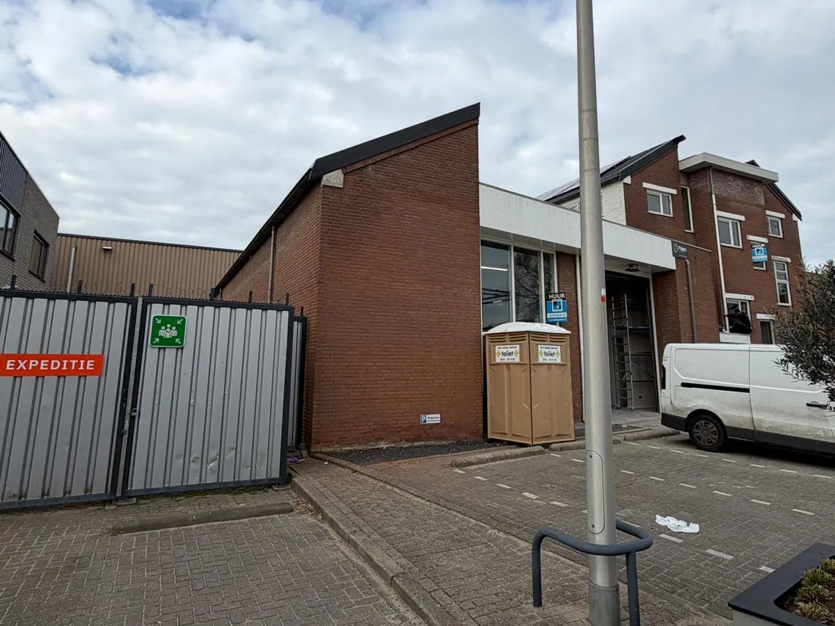 Kopgevel van het bedrijfspand in rode baksteen, voor het schilderwerk