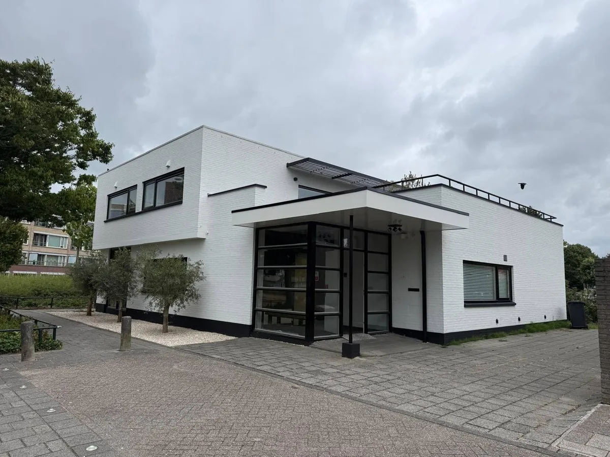 Hetzelfde pand na het schilderwerk: wit geschilderde gevel met zwarte kozijnen, plint en dakrand