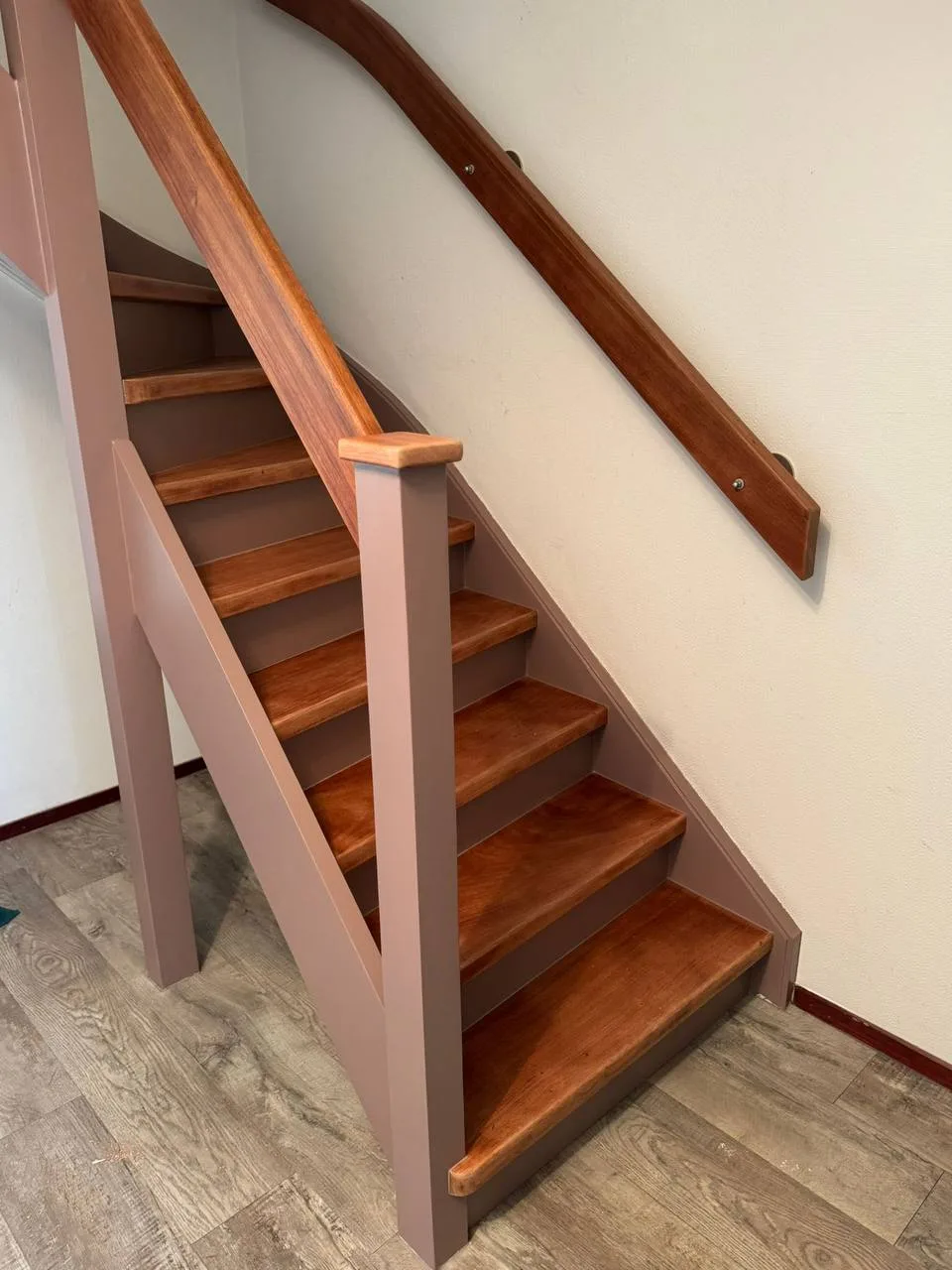 Houten trap met treden in een warme houtkleur en de trapboom in een lichte kleur