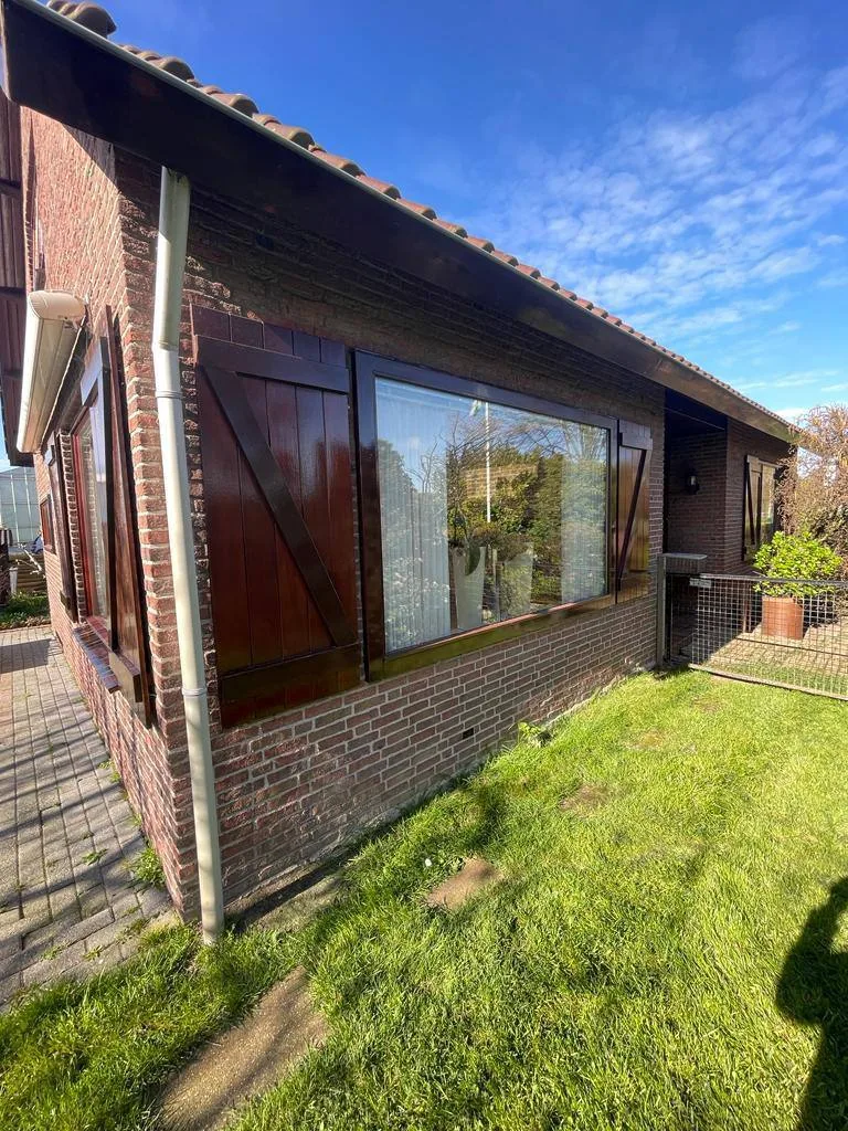 Buitenwand met donker gebeitste houten delen en een groot raam